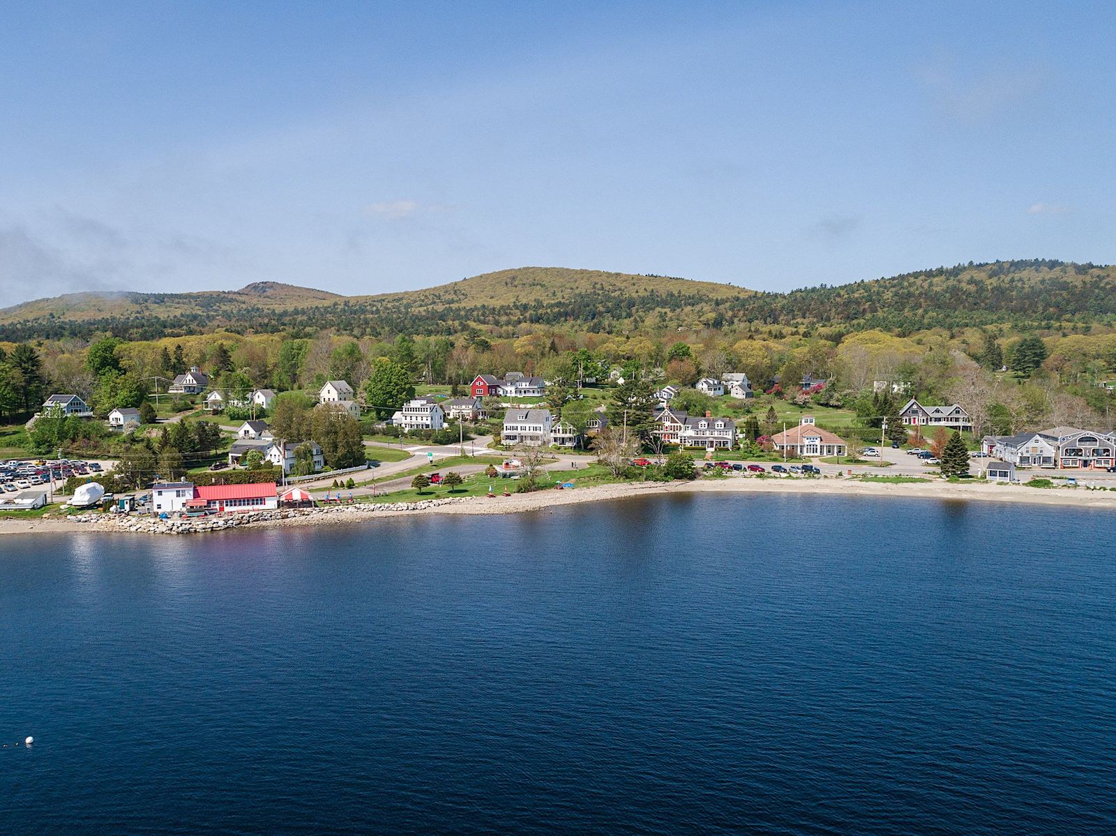 Aerial view of Lincolnville Beach: sand, the bay, town rooftops and distant hills