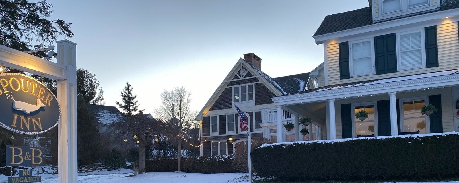 The inn on a snowy night: the SPOUTER INN sign, a B&B sign and a lit NO VACANCY sign, snow on the ground