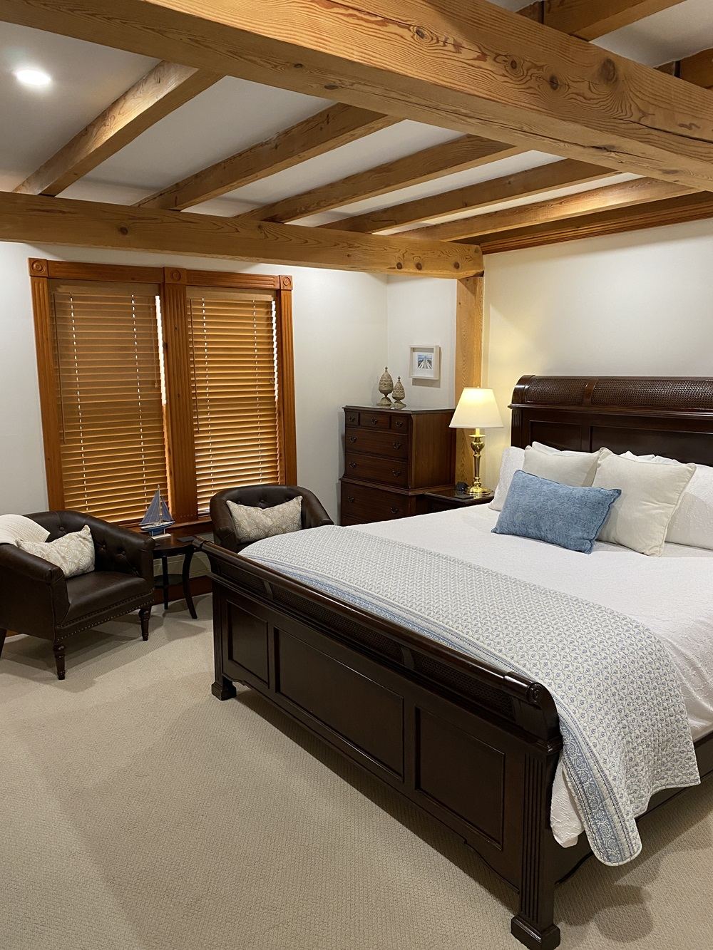 Admiral's Quarters: sleigh bed with blue pillows, two brown leather chairs under exposed wooden beams