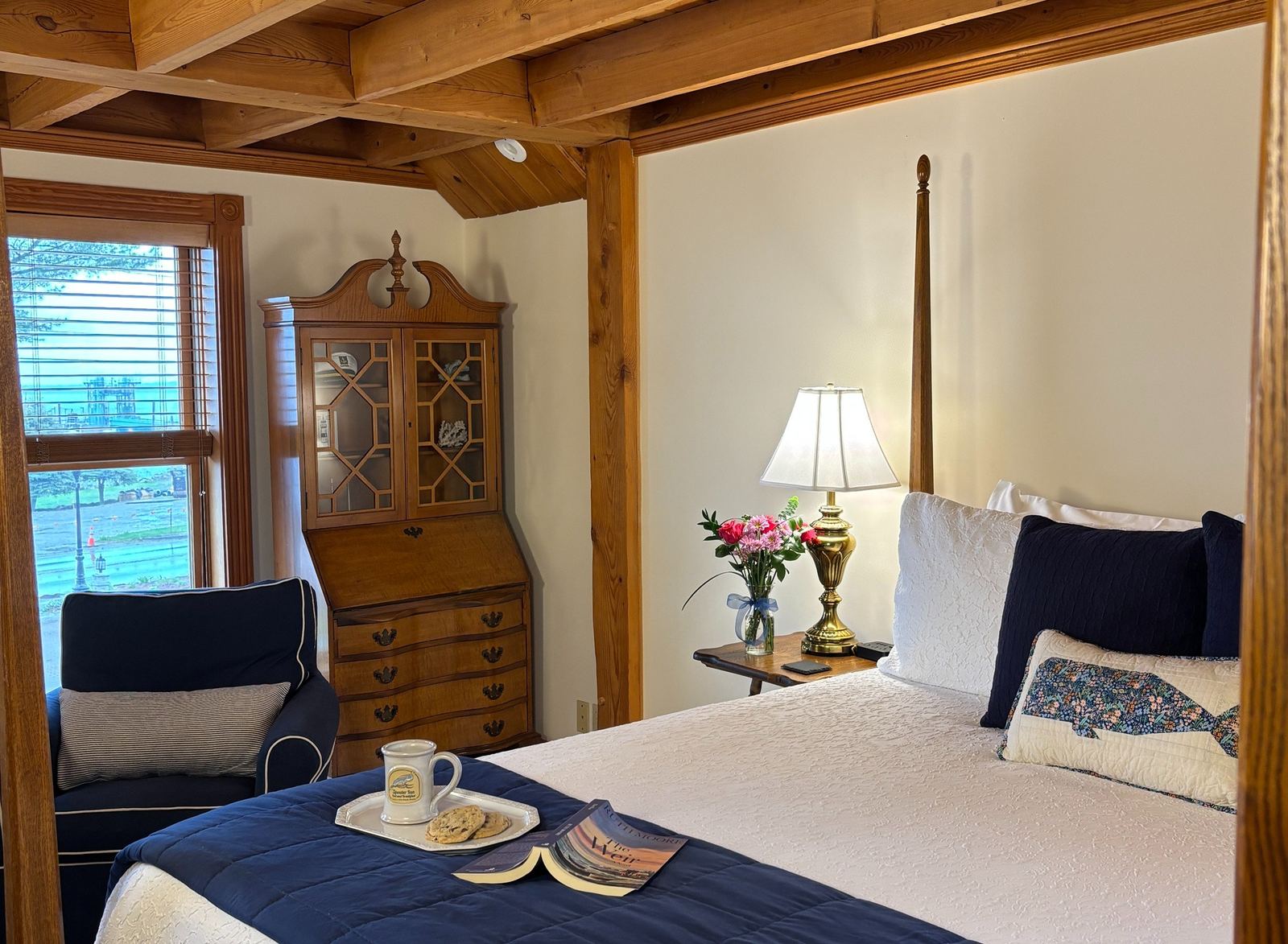 Captain's Quarters: four-poster bed with a blue CAPTAIN pillow, a Spouter Inn mug and cookies on the bed