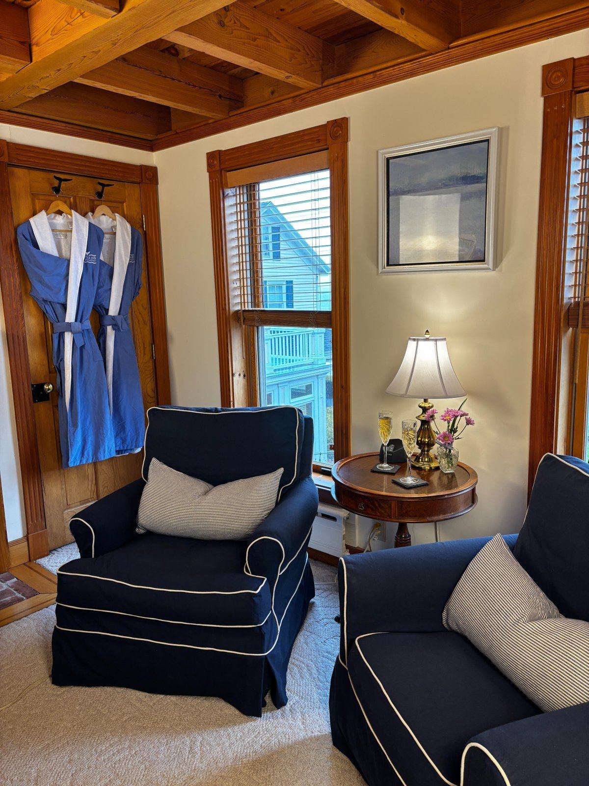 Captain's Quarters sitting area: navy armchairs and a round wooden table, blue robes on the door