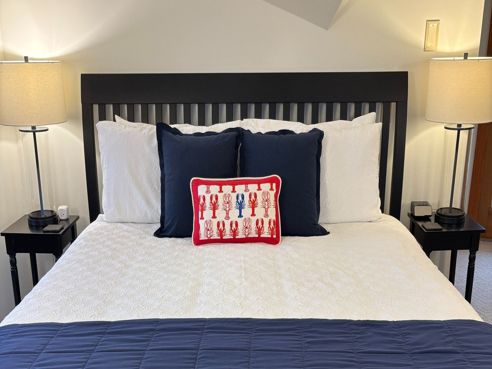 Crow's Nest Suite: lobster-motif accent pillows and deep-blue cushions on a dark headboard bed