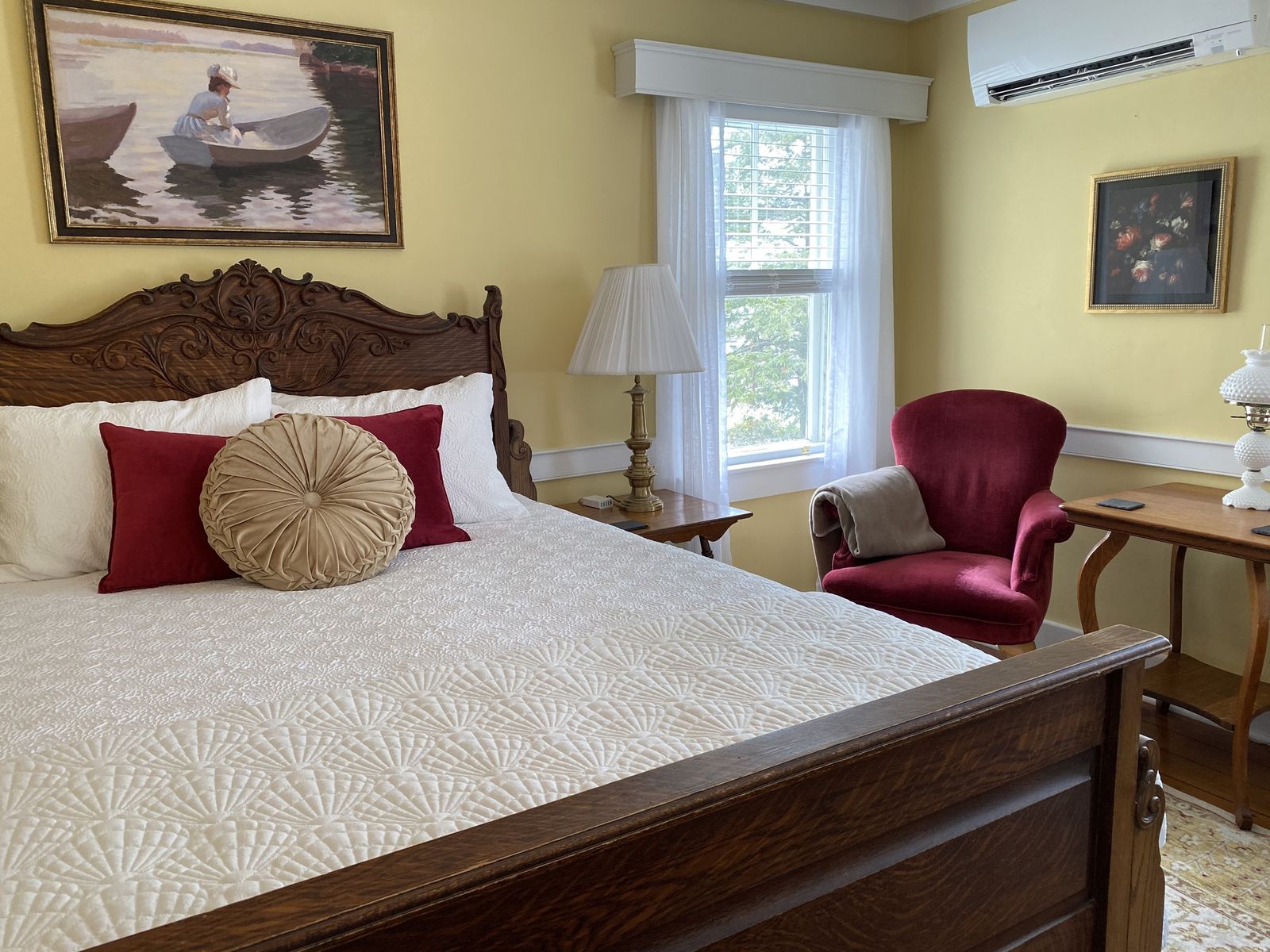First Mate's Quarters: carved wooden headboard, red armchair and ship artwork on the wall